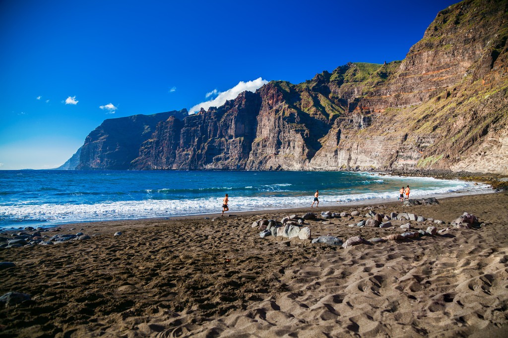 beach Playa de los Guios in Los Gigantes with four running men, Tenerife, Canary Islands, Spain