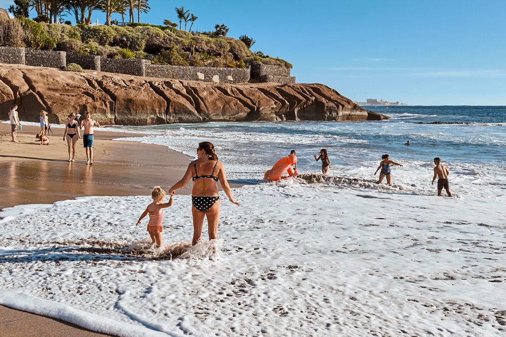 Spain, Canarias islands, Santa Cruz de Tenerife, Adeje - December 20, 2019: Mom with a child on the beach of a sea resort. Tourism and travel. Recreation.