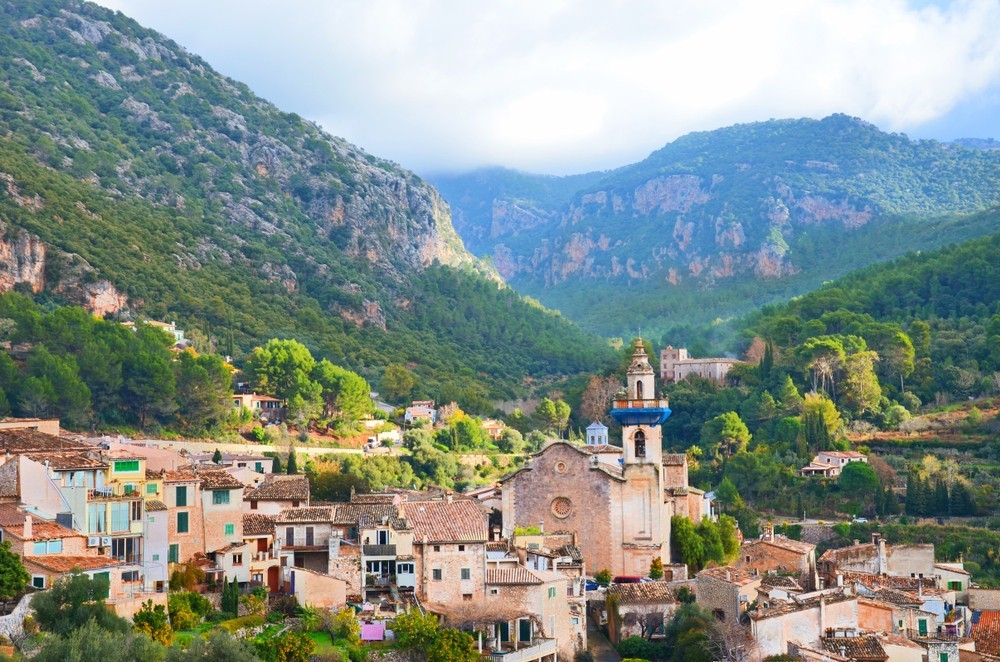 Amazing cityscape of Valldemossa, Mallorca, Spain taken on a sunny winter day. The beautiful spanish village in the valley surrounded by mountains is a popular tourist destination. 