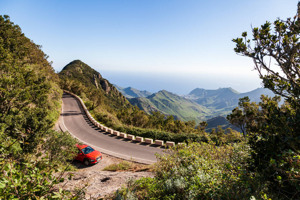 The beautiful landscape of the Tenerife mountains and the winding mountain road of the island of Tenerife. Red car on the frn of the ocean and mountains.