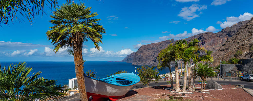 A colourful painted fishing boat on display near the ocean in Los Gigantes, Tenerife, Canary Islands, a picture postcard scenic view of the island. panorama view