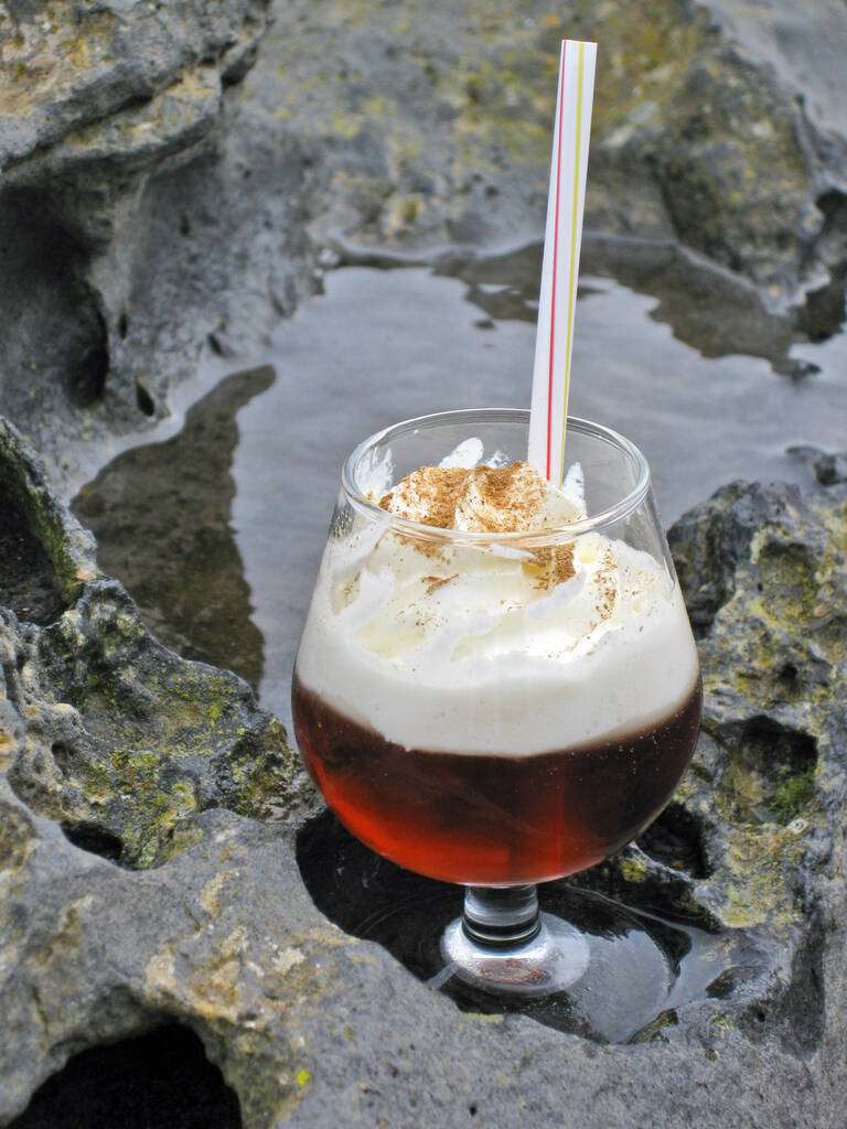 Lanzarote, Canary Islands, Spain. A traditional  Canarian honey-rum ('ron con miel') cocktail served with cream and cinamon on top, the glass placed on a volcanic rock.
