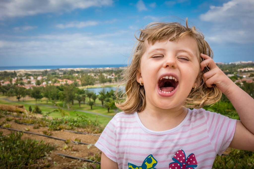 Little girl standing on a viewpoint over Maspalomas in gran Canaria and shouting loudly