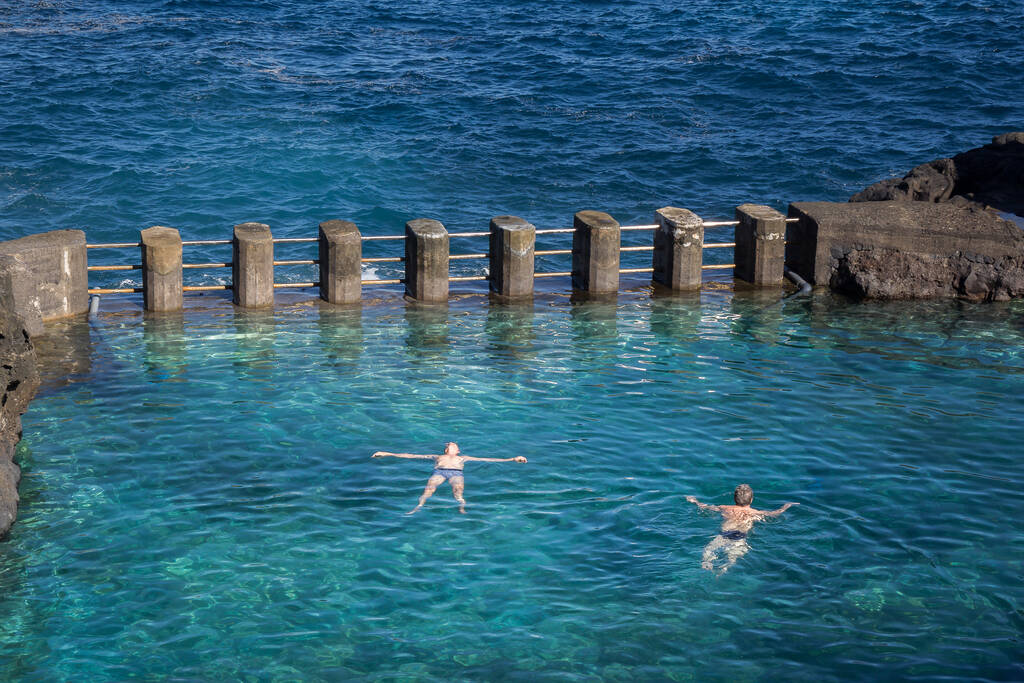Two men swimming in a natural sea water pool in Spain