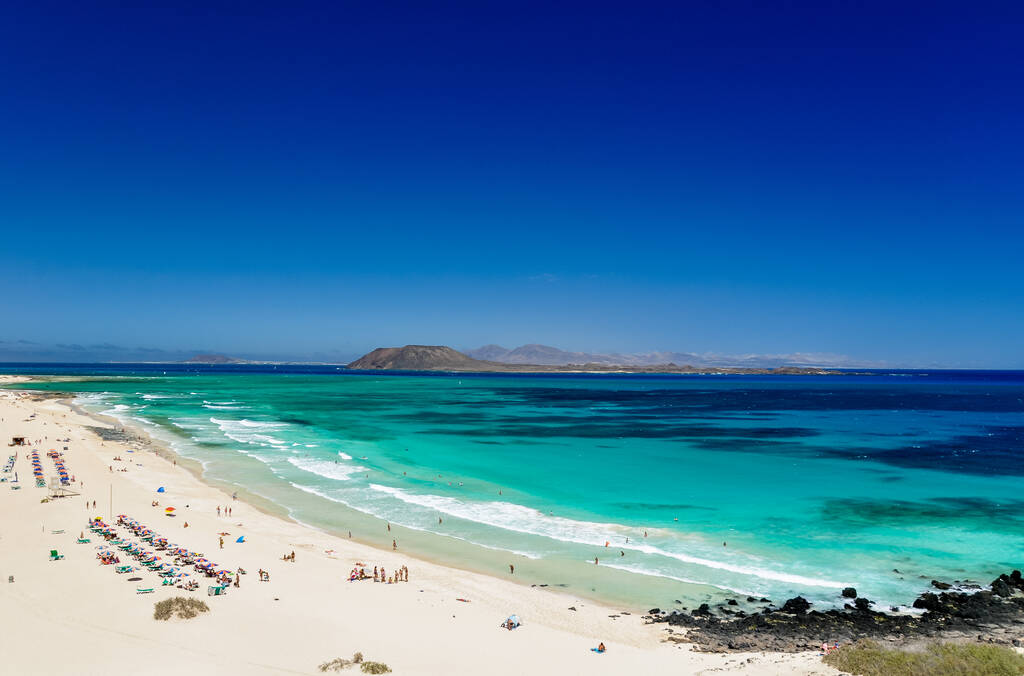 Widok z plaży Corralejo (Grandes Playas de Corralejo) na Fuerteventura, Wyspy Kanaryjskie, Hiszpania, Europa. Piękna turkusowa woda i biały piasek.