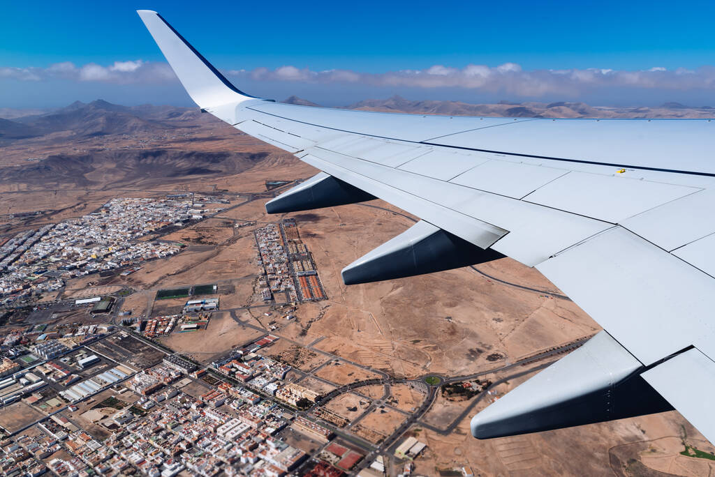 Wing of airplane taking off Fuerteventura Airport, above city. Traveling concept