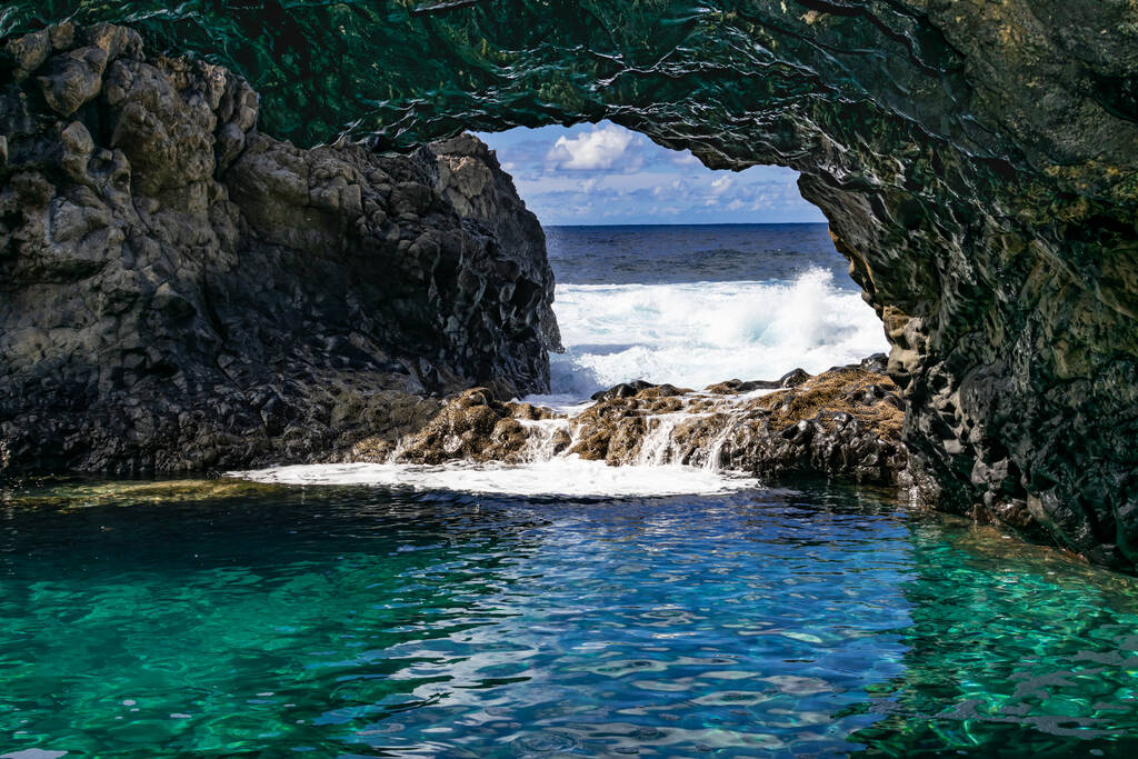 Charco azul volcanic cavern, natural volcanic ocean pool with turquoise ocean water in a volcanic cavern, with sunlight and Atlantic ocean background, Frontera, El Hierro, Canary islands, Spain