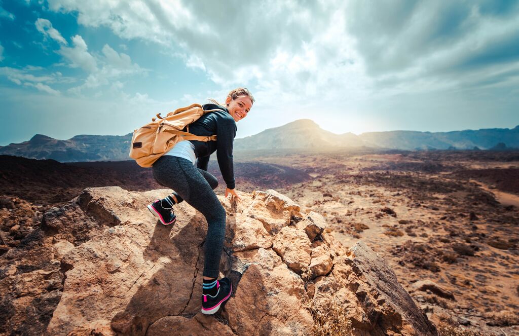 Portret szczęśliwej kobiety wycieczkowicz stojącej na szczycie grzbietu górskiego przed górami - koncepcja sportu i zdrowego stylu życia, licencja: shutterstock/By DavideAngelini