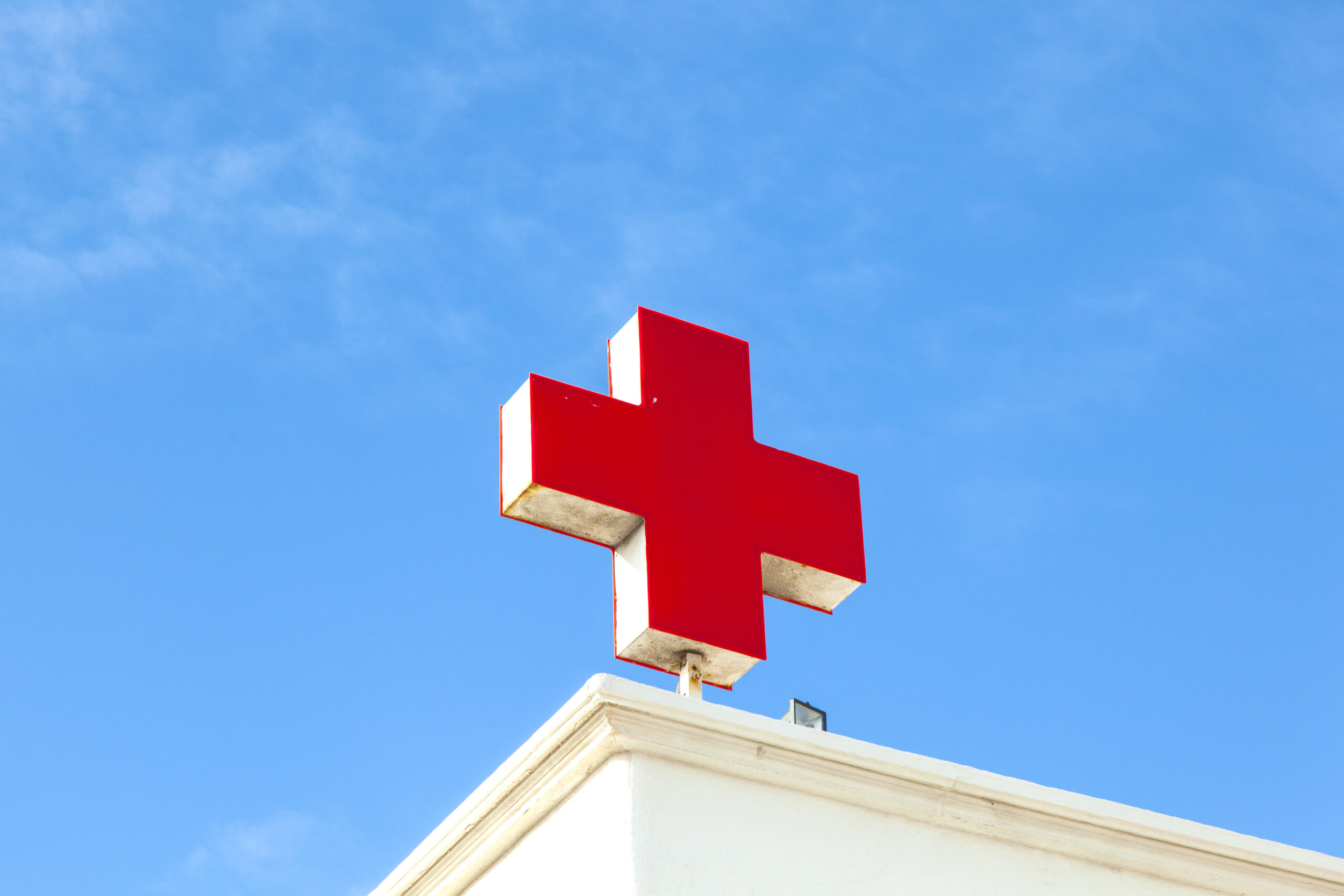 Czerwony krzyż na dachu szpitala symbolizujący pomoc medyczną. Playa Blanca, Hiszpania.